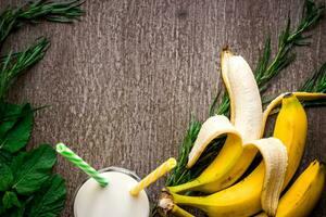 Banana smoothie and fresh banana on wooden table. photo