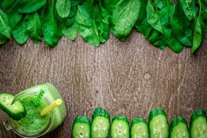 Glass of spinach juice on wooden background photo