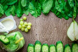 Healthy green smoothie with spinach in a mug against on wooden background photo