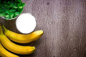 Banana smoothie and fresh banana on wooden table. photo