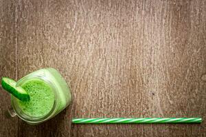 Glass of spinach juice on wooden background photo