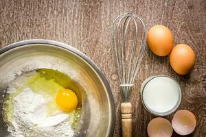 Food ingredients and kitchen utensils for cooking on wooden background photo