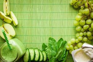 Ingredients for Green detox smoothie. Spinach, grape, yogurt, cucumber and apples on green background photo