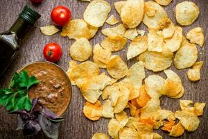 Potato chips with dipping sauce on a wooden table. Unhealthy food on a wooden background. photo