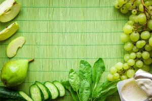 Ingredients for Green detox smoothie. Spinach, grape, yogurt, cucumber and apples on green background photo