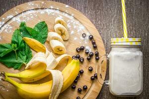 Banana smoothie and fresh banana on wooden table. photo