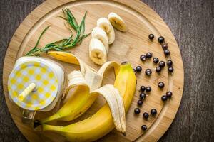 Banana smoothie and fresh banana on wooden table. photo