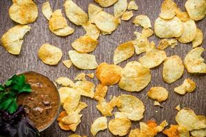 Potato chips with dipping sauce on a wooden table. Unhealthy food on a wooden background. photo