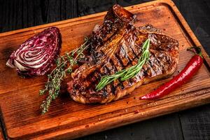 Medium rare grilled steak on rustic cutting board with rosemary and spices , dark rustic wooden background, top view photo