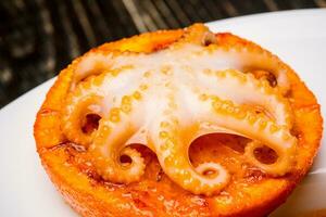 Seafood. Small octopus baked on an orange slice. Close-up photo