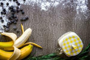 Banana smoothie and fresh banana on wooden table. photo