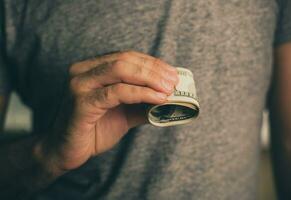 un hombre sostiene dolares en su manos foto