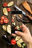 un joven mujer tomando foto de comida en teléfono inteligente, fotografiando comida con móvil cámara