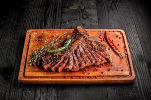 rebanado medio raro A la parrilla filete en rústico corte tablero con Romero y especias , oscuro rústico de madera fondo, parte superior ver foto