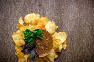 Potato chips with dipping sauce on a wooden table. Unhealthy food on a wooden background. photo