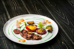 Sliced meat with fresh herbs, vegetables and spices on a white plate on a black wooden background, top view photo