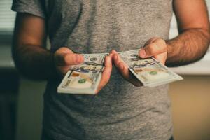 un hombre sostiene dolares en su manos foto