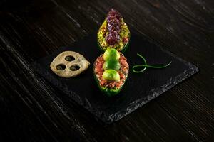 Salmon tartare and avocado salad on a black background photo