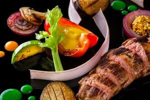 Sliced meat with fresh herbs, vegetables and spices on black background, top view photo