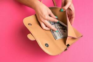 Woman's hand removing money from little bag, studio shot photo