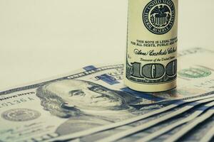 A coiled 100 dollar bill which rests on another angled 100 dollar bill isolated on white background photo