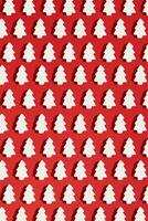 Pattern made of white christmas decoration with christmas tree on red background. Christmas wallpaper. photo