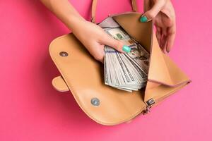 Woman's hand removing money from little bag, studio shot photo