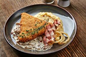 Chicken schnitzel with herb, mashed potatoes and mushrooms sauce on plate on wooden table background. Healthy food. photo