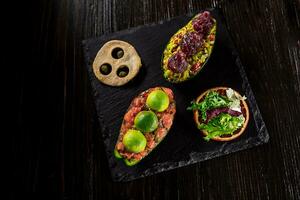 Salmon tartare and avocado salad on a black background photo