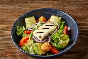 Fried Tofu Salad with Cucumbers, Tomatoes, Avocado and Sesame Seeds. Homemade asian vegetable and tofu salad in ceramic bowl on wooden background. photo