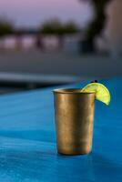 Rum cola casual cocktail with ice cubes and lime at summer bar stand background. photo