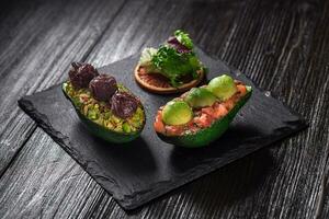 salmón tartar y aguacate ensalada en un negro antecedentes foto