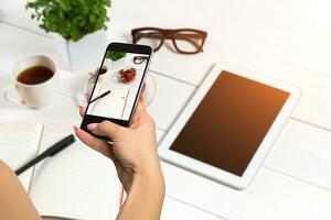 Young girl using Photography of smartphone of work table on mobile camera display while shooting. photo