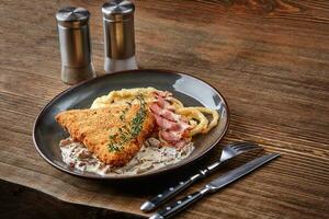 Chicken schnitzel with herb, mashed potatoes and mushrooms sauce on plate on wooden table background. Healthy food. photo