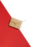Craft paper present box tied from rope on red and white background. Pattern photo