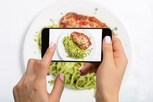 un joven mujer tomando foto de comida en teléfono inteligente, fotografiando comida con móvil cámara