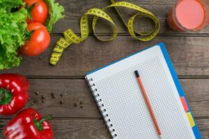 Glass of tomato juice with vegetables and measuring tape on table close-up photo