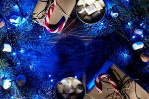 Christmas hot drink. Cocoa with marshmallow, garland and spruce branches on a wooden background. Top view photo