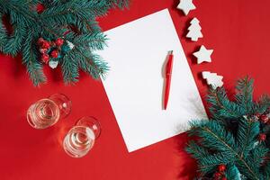 Red pen and notepad on red table decorated with a fir branch. The background for the text. photo