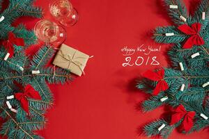 Two glasses of champagne with Christmas tree branch and small gift on a red background photo