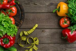 Vegetables and in measure tape in diet on wooden background. Top view. photo