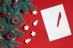 Red pen and notepad on red table decorated with a fir branch. The background for the text. photo