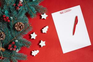 Red pen and notepad on red table decorated with a fir branch. The background for the text. photo