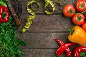 Vegetables and in measure tape in diet on wooden background. Top view. photo