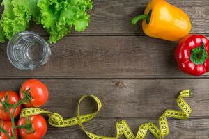 Glass of water with vegetables and measuring tape on table close-up photo