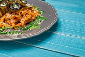 Pasta with eggplants, tomato, cheese and arugula photo