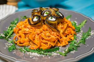 Pasta with eggplants, tomato, cheese and arugula photo