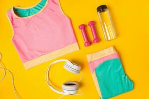 Sport equipment and clothes with mobile phone on yellow background. Top view photo