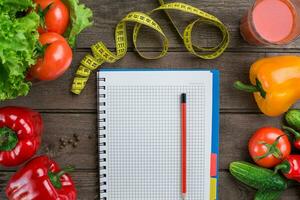 Glass of tomato juice with vegetables and measuring tape on table close-up photo