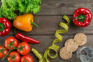 Glass of water with vegetables and measuring tape on table close-up photo